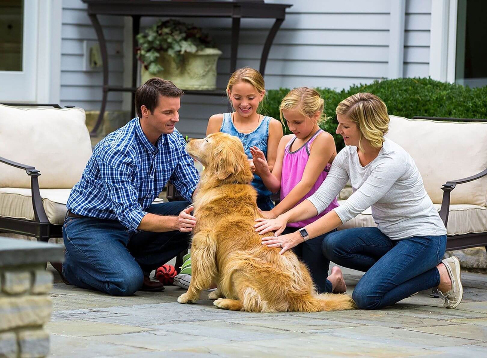 Happy family petting their Golden Retriever on the patio in Chelan, enjoying time together in a safe yard protected by an invisible dog fence.