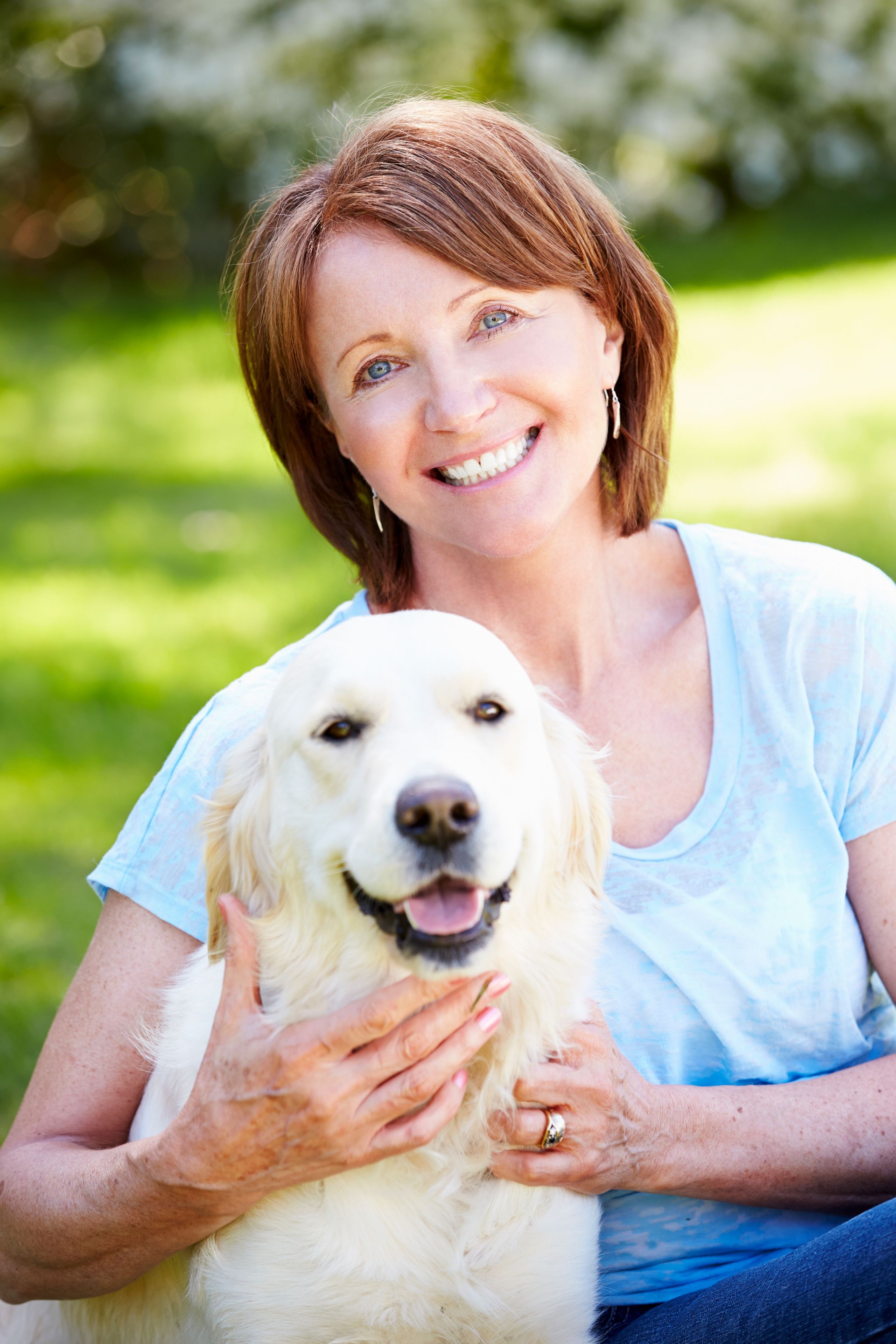 Portrait Of Mature Woman Sitting In Field With Dog
